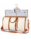 The Folvia Bag in Sand with the garment section open and a blazer on its hanger